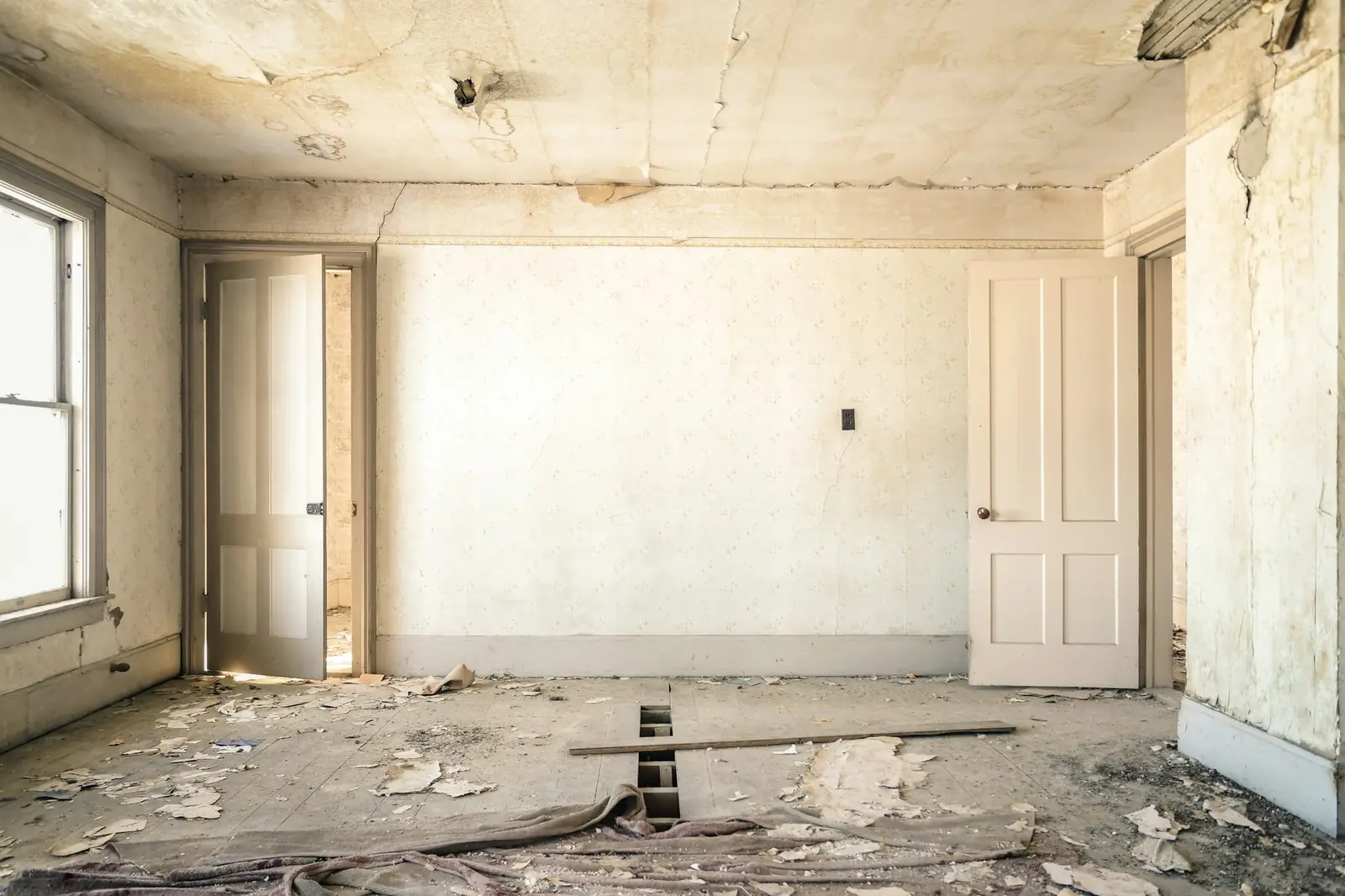 Empty room in an older house with plaster removed and debris on the floor